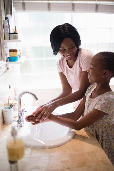 Мама смотрит на дочь, когда моет руки. — стоковое фото