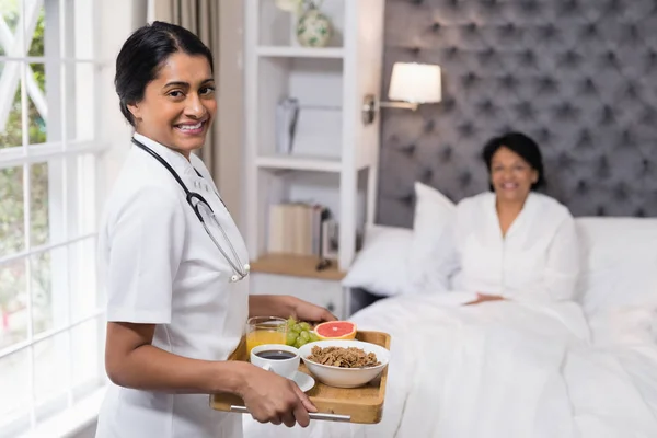 Enfermera sirviendo desayuno a paciente en casa — Foto de Stock