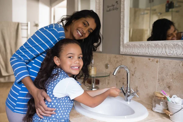 Meisje met moeder wassen handen — Stockfoto