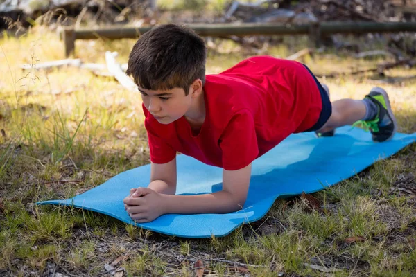 Niño haciendo ejercicio en la alfombra de ejercicio — Foto de Stock