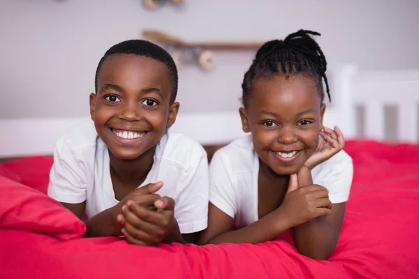Siblings lying together on bed — Stock Photo, Image
