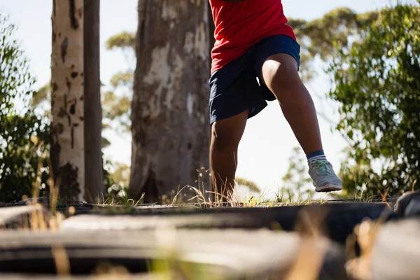 Boy running over tyres — Stock Photo, Image