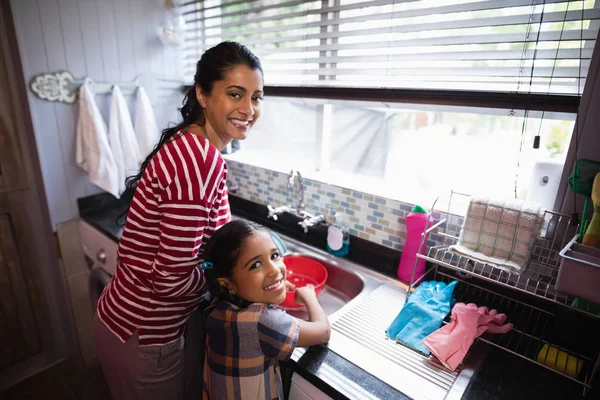 Улыбающаяся девочка помогает маме на кухне — стоковое фото