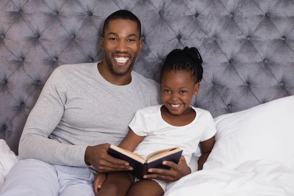 Hombre con hija leyendo libro en la cama —  Fotos de Stock