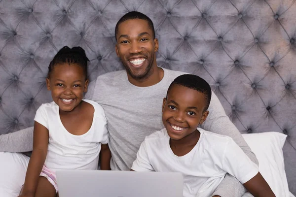 Father with children sitting on bed — Stock Photo, Image