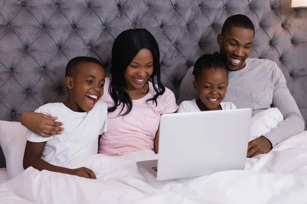 Familie met behulp van de laptop terwijl samen op bed — Stockfoto