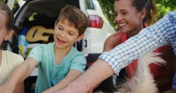 Сім'я сидить зі своїм собакою — стокове відео