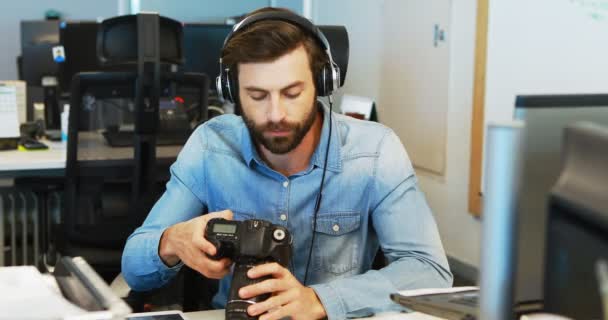 Diseñador gráfico masculino con auriculares usando cámara — Vídeo de stock