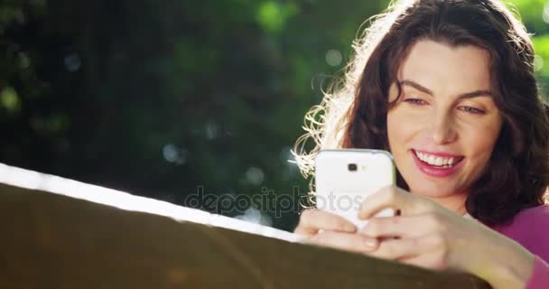 Woman using mobile phone in park — Stock Video