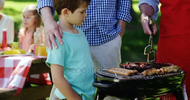 Familia preparando comida en la barbacoa — Vídeos de Stock