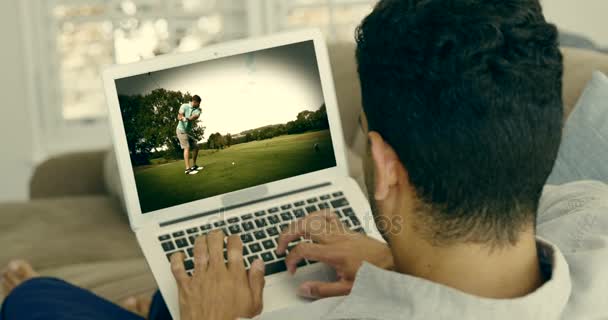 Homme regardant le golf sur ordinateur portable dans le salon — Video
