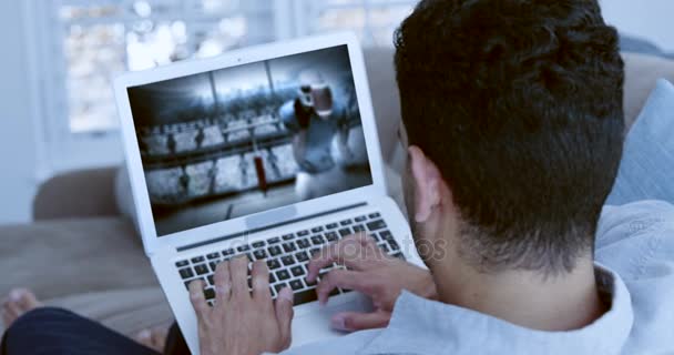 Мужчина смотрит американский футбольный матч на ноутбуке — стоковое видео