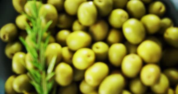 Verse groene olijven en rozemarijn in een kom — Stockvideo