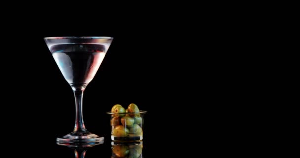 Оливковая палочка падает в коктейльный бокал — стоковое видео