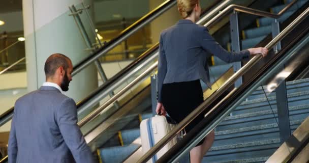 Businessman and woman climbing staircase with luggage — Stock Video