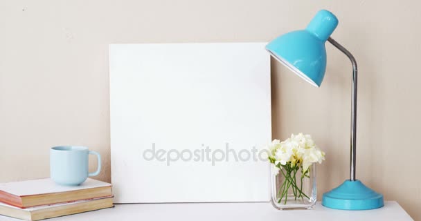 Pilha de livros, placa em branco, vaso de flores, xícara de chá e lâmpada de mesa — Vídeo de Stock