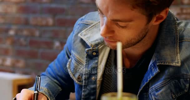 Homme écrivant dans sa laiterie avec du jus sur la table — Video