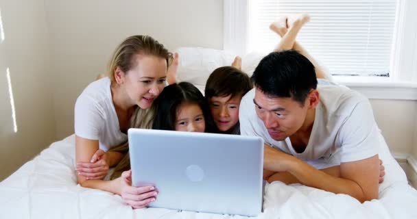 Familia feliz relajarse en la cama y el uso de ordenador portátil — Vídeo de stock