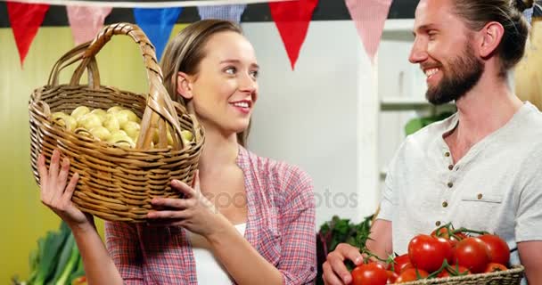 Pareja interactuando mientras sostiene verduras en la cesta — Vídeos de Stock