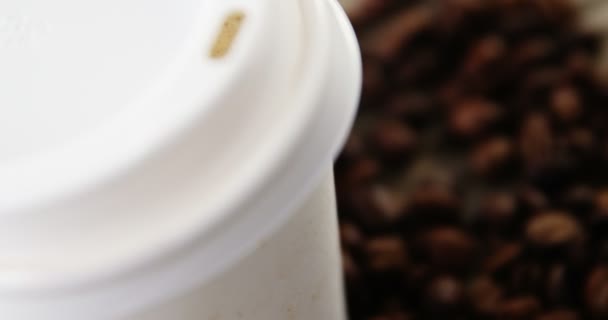 Одноразова чашка з кавовими зернами на дерев'яній дошці — стокове відео