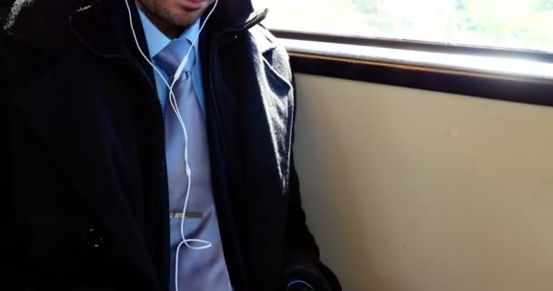 Бизнесмен, использующий мобильный телефон во время прослушивания музыки — стоковое видео
