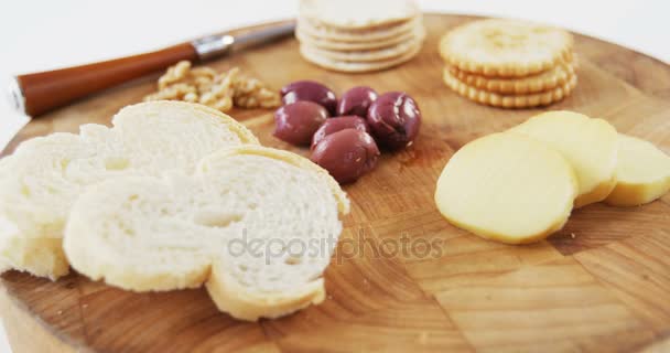 Rebanadas de pan, galletas, aceitunas, nuez y cuchillo sobre tabla de madera — Vídeo de stock