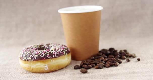 Copo de café descartável e donut de chocolate e grão de café com polvilhas — Vídeo de Stock