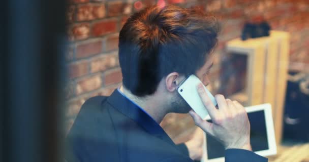 Man talking on mobile phone while using digital tablet — Stock Video