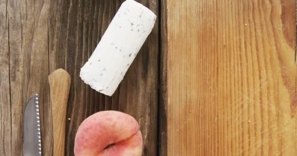Κατσικίσιο τυρί, σπόρους μουστάρδας, μαχαίρι και ροδάκινο στο ξύλινο τραπέζι — Αρχείο Βίντεο