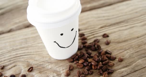 Cara sonriente en taza desechable con granos de café en saco — Vídeos de Stock