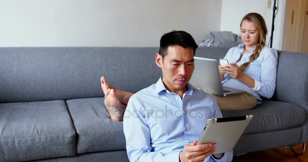 Hombre usando tableta digital mientras que la mujer usando el teléfono móvil — Vídeo de stock