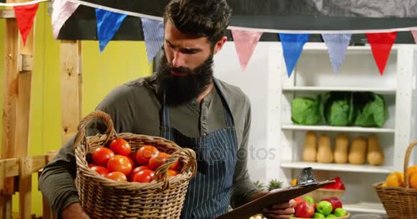 Pessoal masculino olhando para a lista de verificação e segurando uma cesta de tomates — Vídeo de Stock