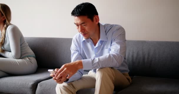 Mann benutzt Handy während er auf Sofa sitzt — Stockvideo