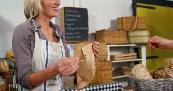 Mitarbeiterinnen geben Frau in Bäckereifiliale gepacktes Brot — Stockvideo