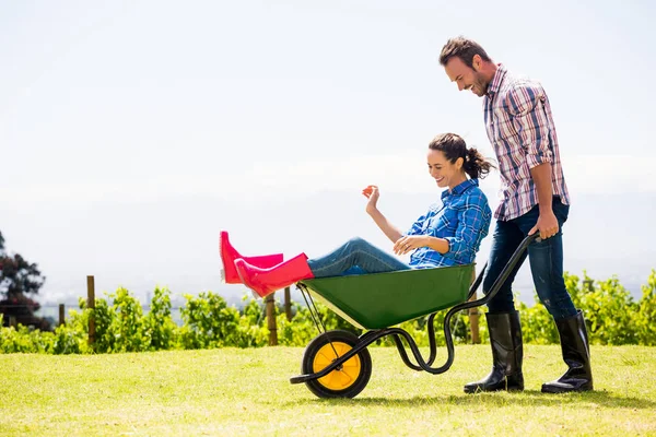 Man pushing woman sitting in wheelbarrow — Stock Photo, Image