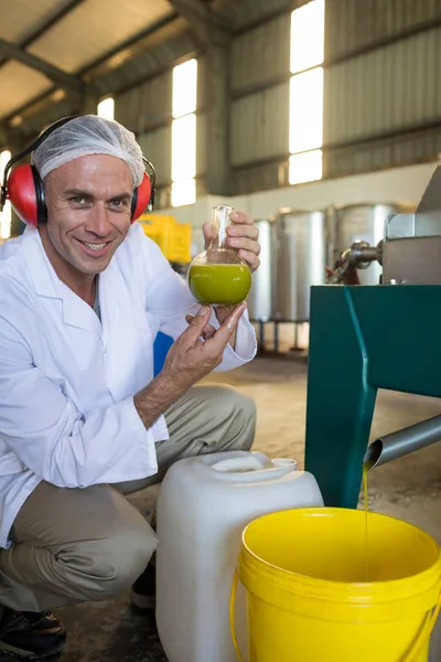 Técnico que examina o azeite produzido a partir da máquina — Fotografia de Stock