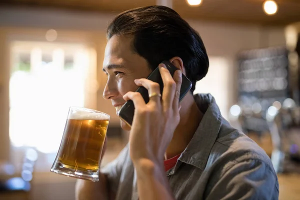 Homme prenant une bière tout en parlant au téléphone — Photo