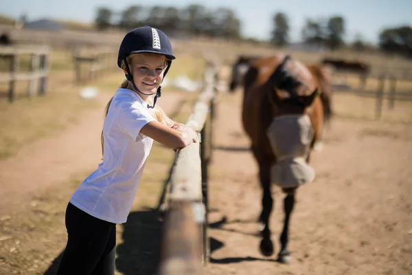 Menina inclinada na cerca e olhando para cavalos — Fotografia de Stock