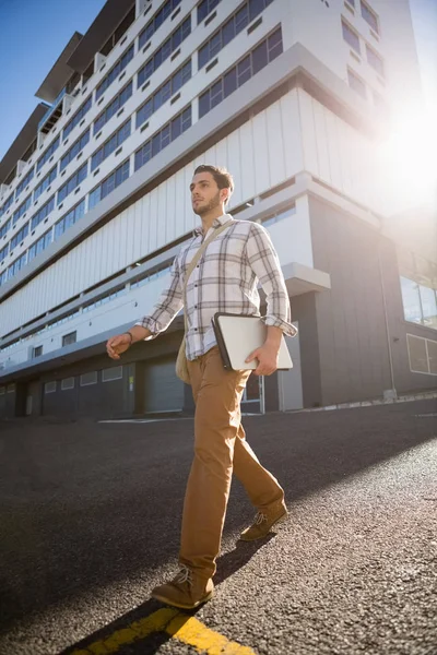 Ο άνθρωπος που κατέχουν φορητό υπολογιστή ενώ το περπάτημα στην πόλη — Φωτογραφία Αρχείου