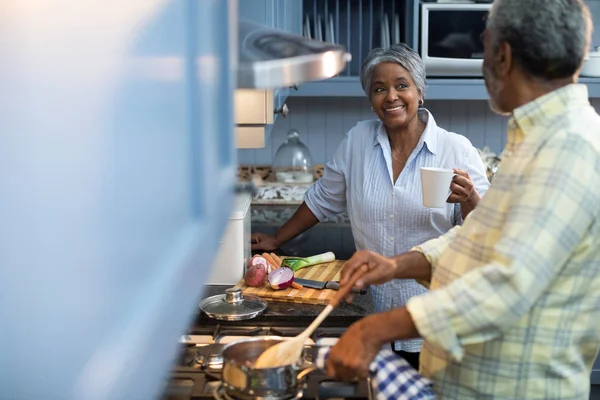 Frau im Gespräch mit Mann bei der Essenszubereitung — Stockfoto