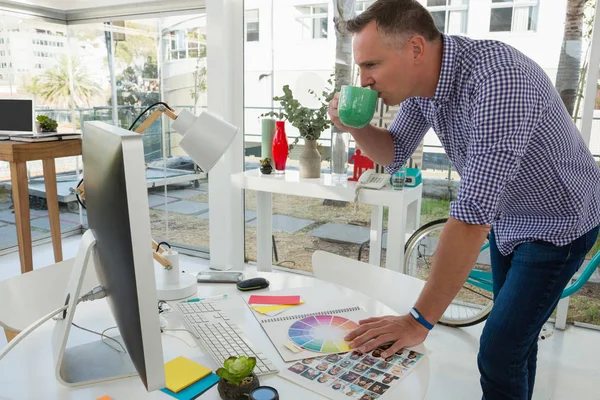 Designer looking at computer while having drink — Stock Photo, Image