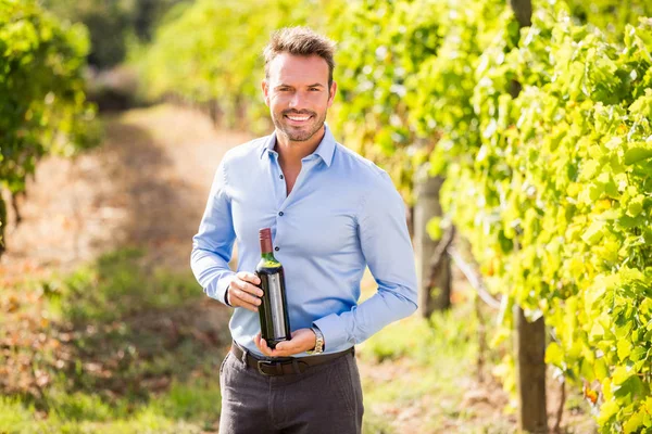 Uśmiechnięty mężczyzna trzymając butelkę wina — Zdjęcie stockowe