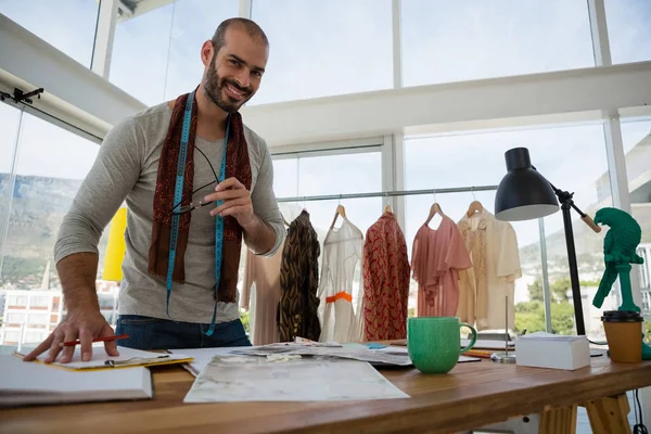 Retrato de designer sorridente em pé à mesa — Fotografia de Stock