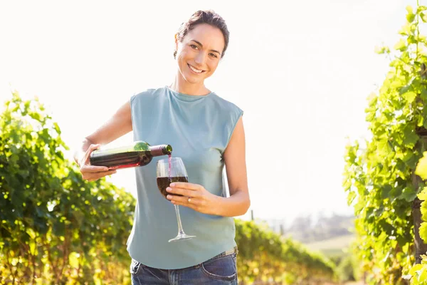 Mulher derramando vinho tinto de garrafa em vidro — Fotografia de Stock