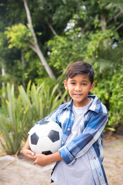 Улыбающийся мальчик держит футбольный мяч — стоковое фото
