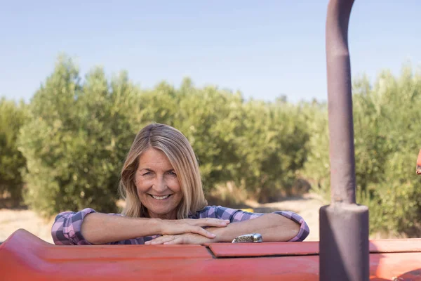 Woman leaning on tractor in olive farm — Stock Photo, Image