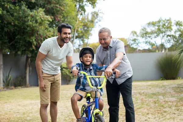 Pai e avô assistindo menino para andar de bicicleta — Fotografia de Stock