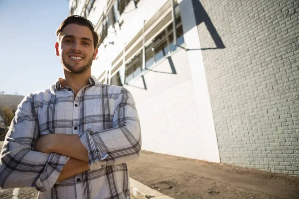 Homem com braços cruzados de pé por construção — Fotografia de Stock