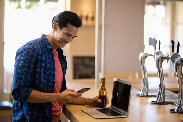 Homme utilisant un téléphone portable au comptoir — Photo