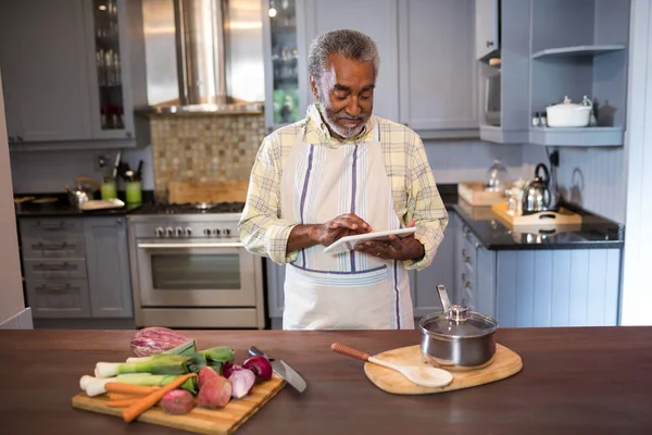 Homme utilisant un ordinateur tablette pendant la cuisson des aliments — Photo